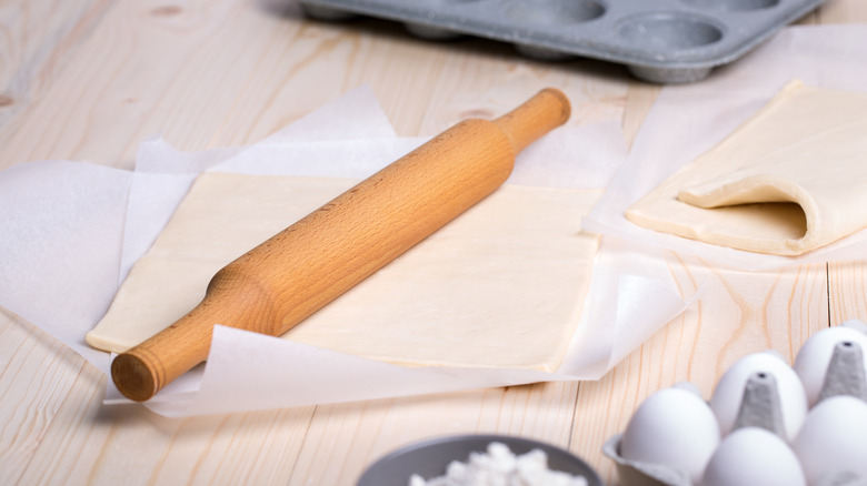 Wax paper and wood rolling pin on counter with sheets of dough