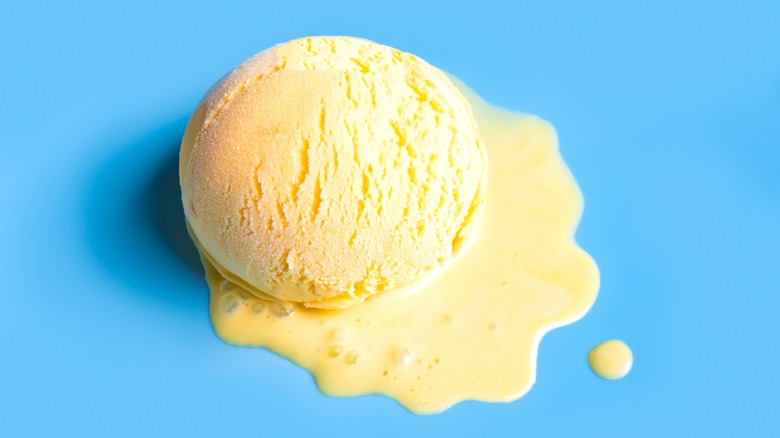 A scoop of vanilla ice cream is melting on a blue background