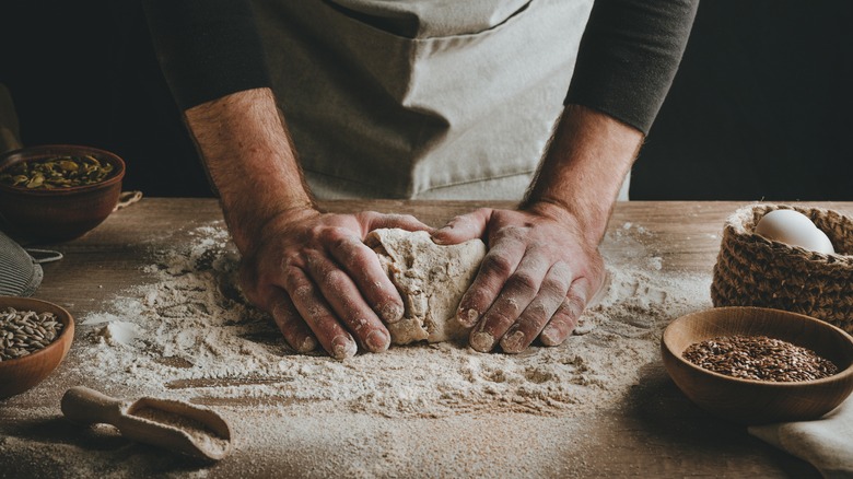 Person kneading dough with flour