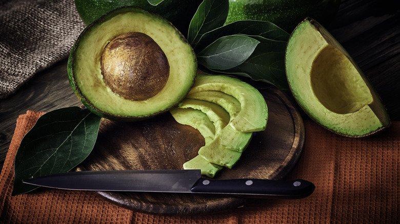 Sliced avocado with knife on a cutting board