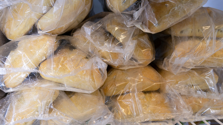 Frozen bags of bread sit on top of each other on a freezer shelf