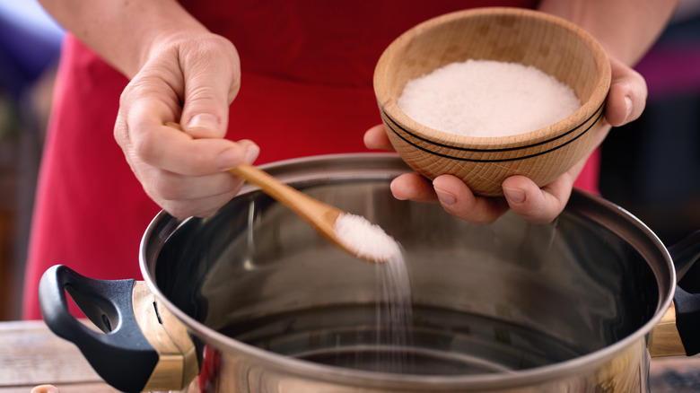 Hands adding salt to pot