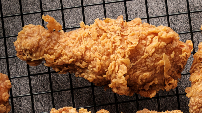 A piece of freshly fried chicken rests on a wire rack, keeping it crispier for longer.