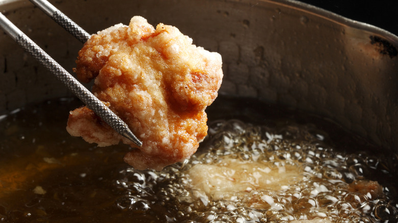 A piece of Japanese double fried chicken is being taken out of hot oil.