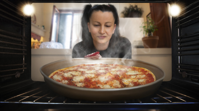 Person removes hot pizza from an oven