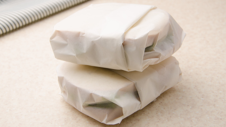 Two stacked sandwiches wrapped in parchment paper