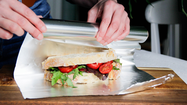 A cook wrapping a sandwich in aluminum foil