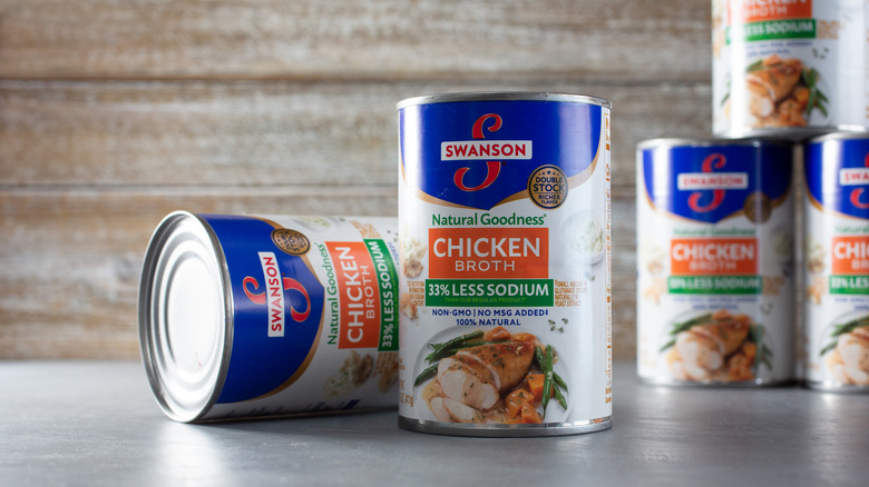 Cans of Swanson chicken broth, with one standing upright, and one tipped on its side