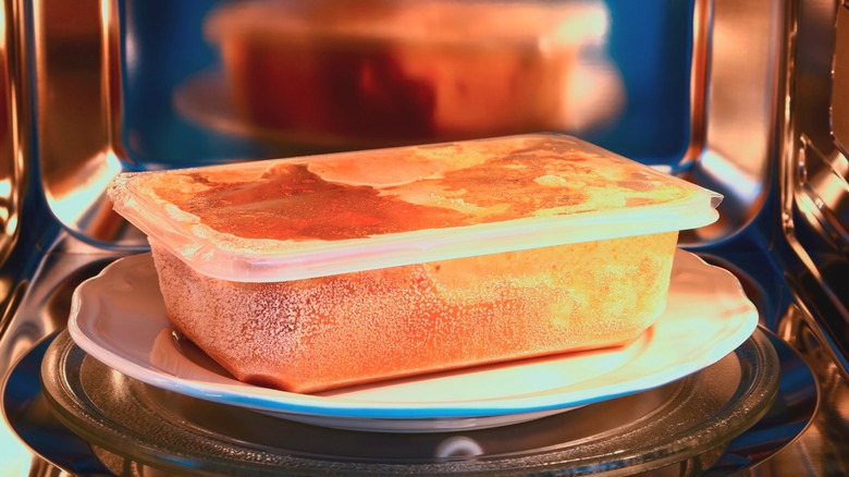 A container of frozen food in a microwave