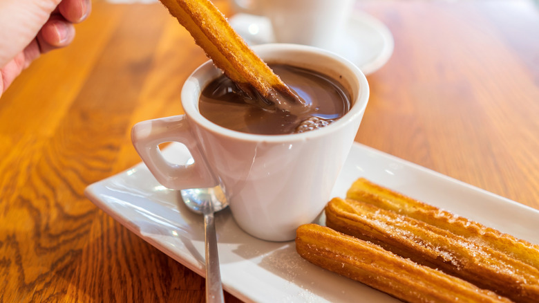 Churro Being Dipped Into Spanish Hot Chocolate