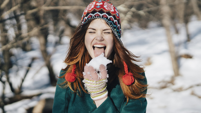 Person eating a handful of snow outside