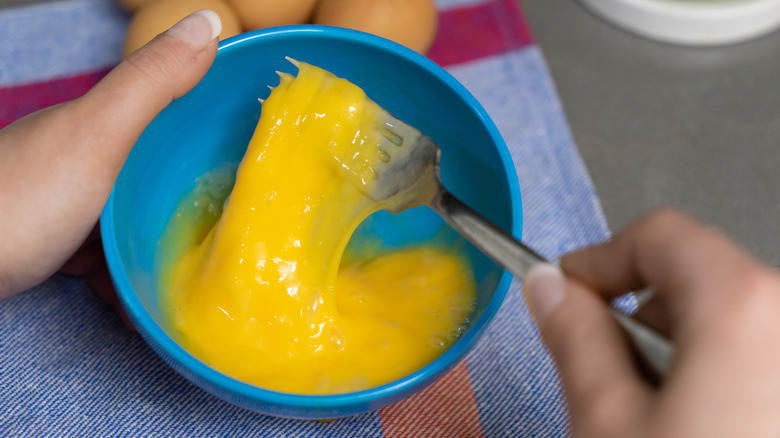 Eggs being beaten in blue bowl with fork