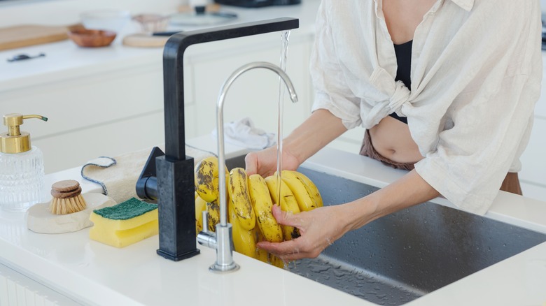 Woman washes bananas in a sink