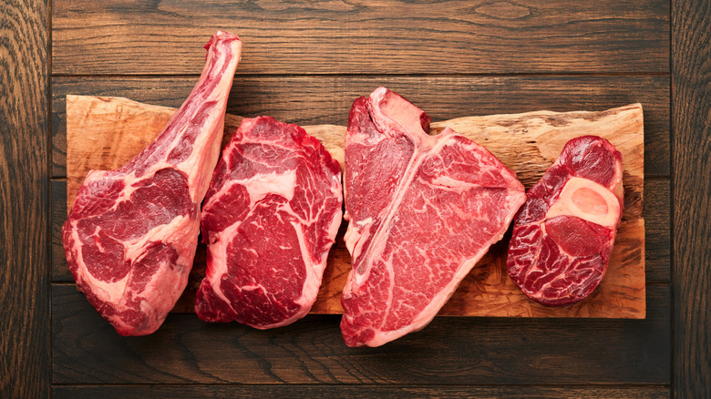 Four different styles of rare steak sit on a wooden table