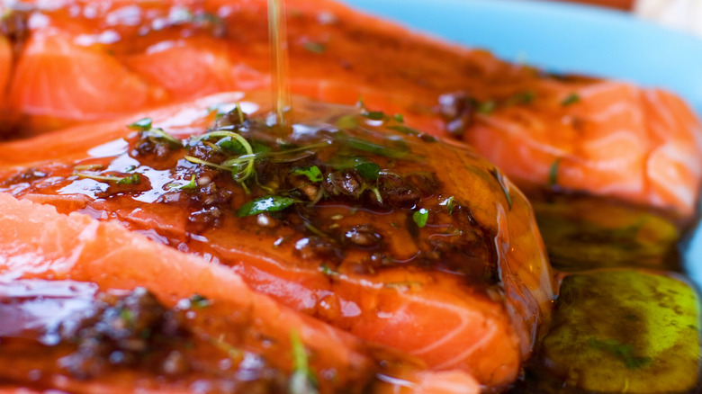 A marinated piece of salmon has oil poured onto it