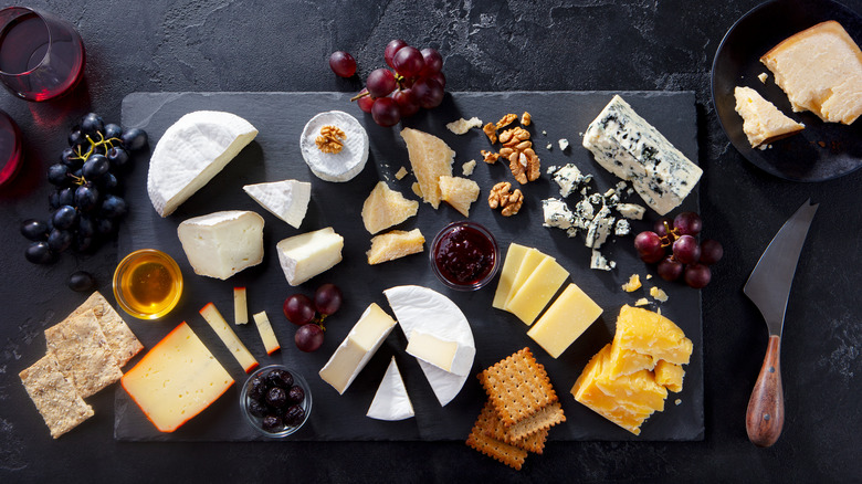 Various cheese, crackers on slate board