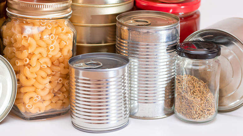 Cans sit among jars and other nonperishables in a pantry