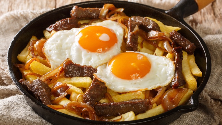 Fries, onion, meat, and eggs in skillet