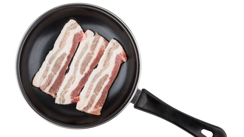raw bacon in a cold pan on white background