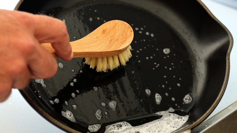 person scrubbing cast iron pan