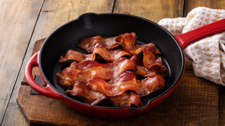 Red cast iron skillet with bacon inside