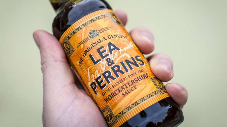 Hand holding a bottle of Worcestershire sauce