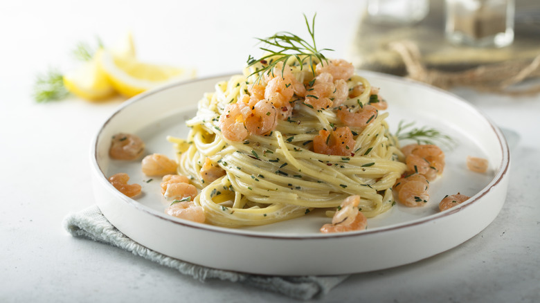 White plate with shrimp pasta with dill