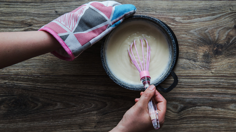 Bechamel sauce being whisked in pan