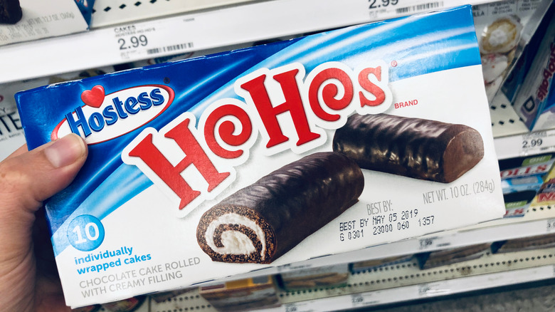 A person holds a box of Hostess HoHos in a grocery store