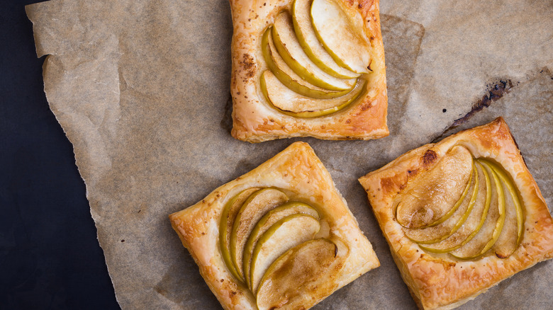 Three puff pastry apple tarts on wax paper