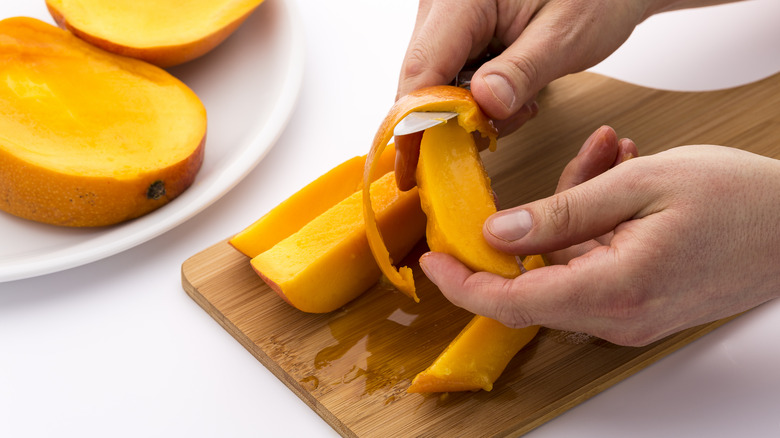 Person peeling a mango