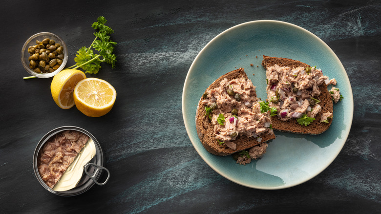 tuna salad sandwich on a blue plate with lemons