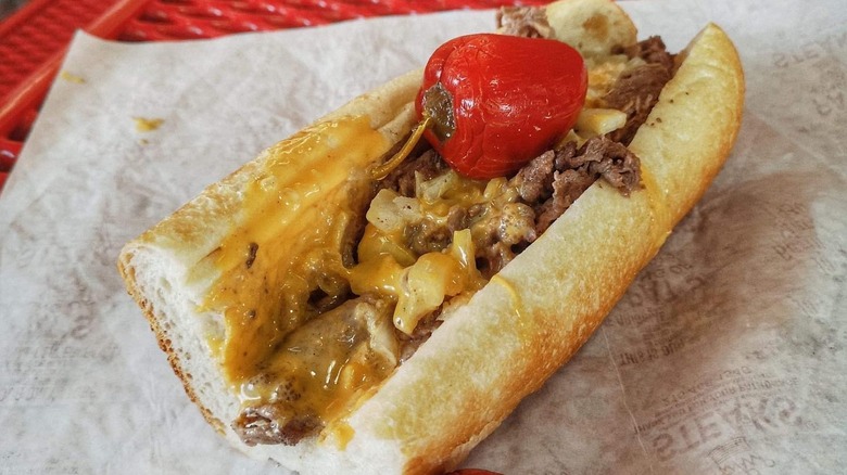 A juicy Philly cheesesteak topped with a spicy red pepper from Geno's