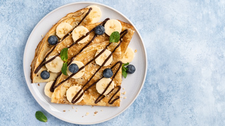 Crepe topped with banana slices and blueberries