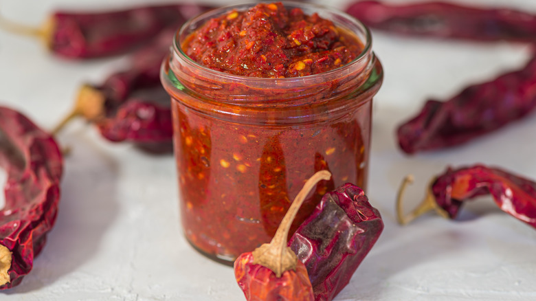 Jar of homemade harissa sauce surrounded by chiles