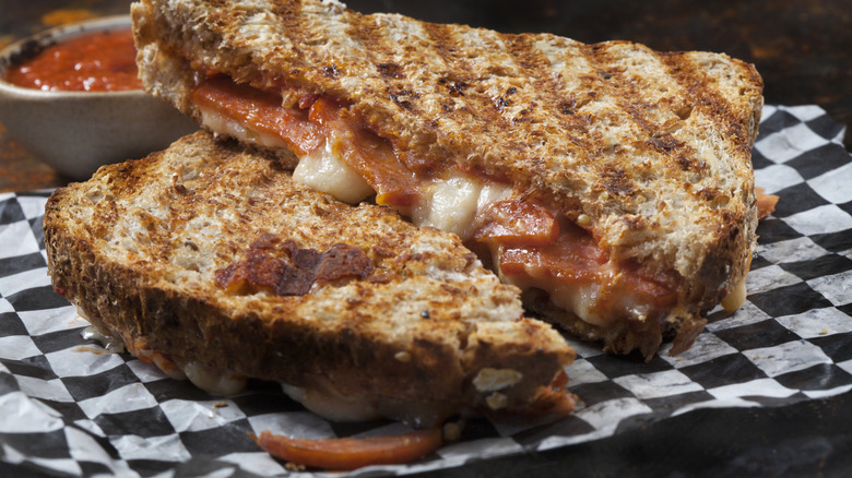 Grilled cheese spinach and tomato sandwich on checkered paper