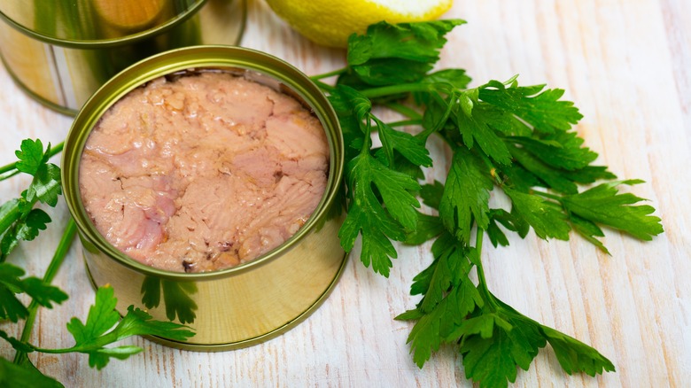 Canned tuna next to herbs and a lemon