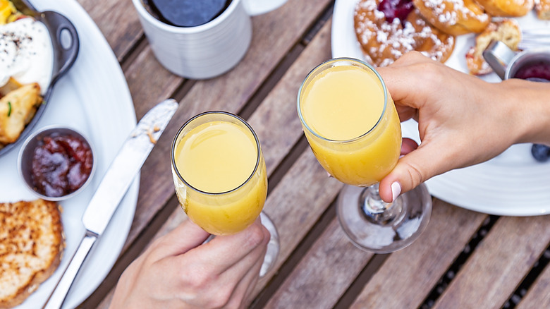 Hands holding mimosas at brunch