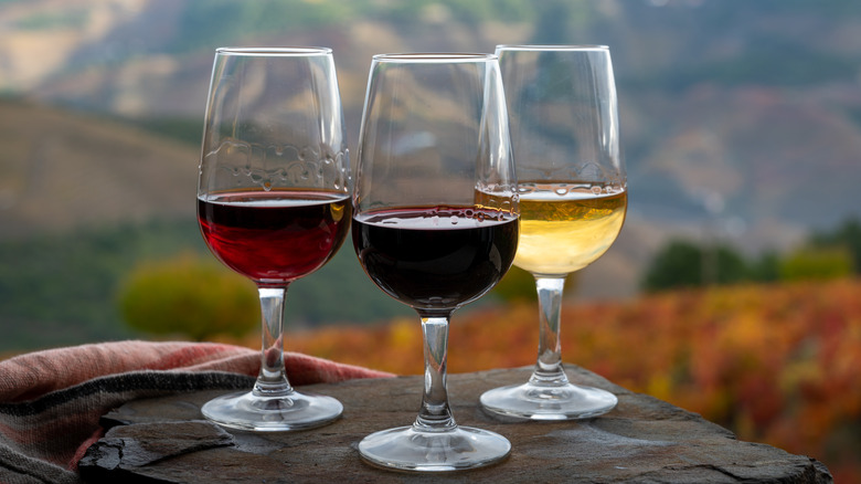 Three glasses of port on a table with vineyard in the background