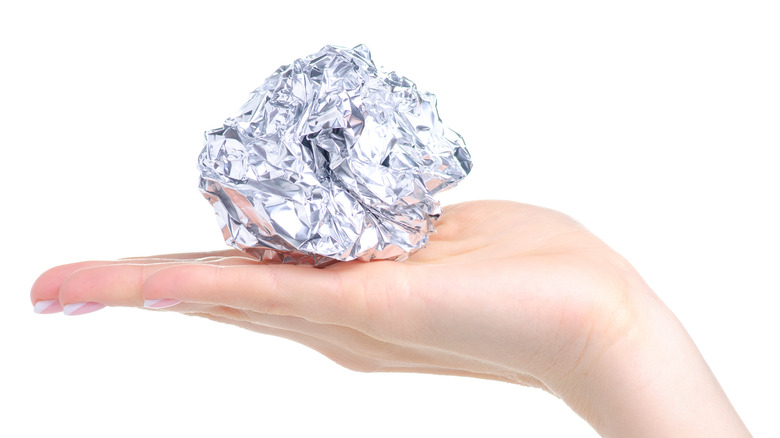 Hand holding a ball of aluminum foil