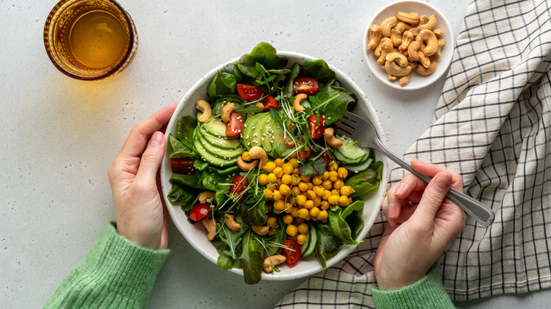 Overhead shot of white bowl filled with green salad avocado tomato and chickpeas