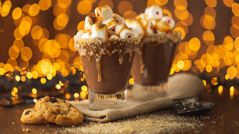 Two cups of hot chocolate with caramel-dipped rims and toasted marshmallows.