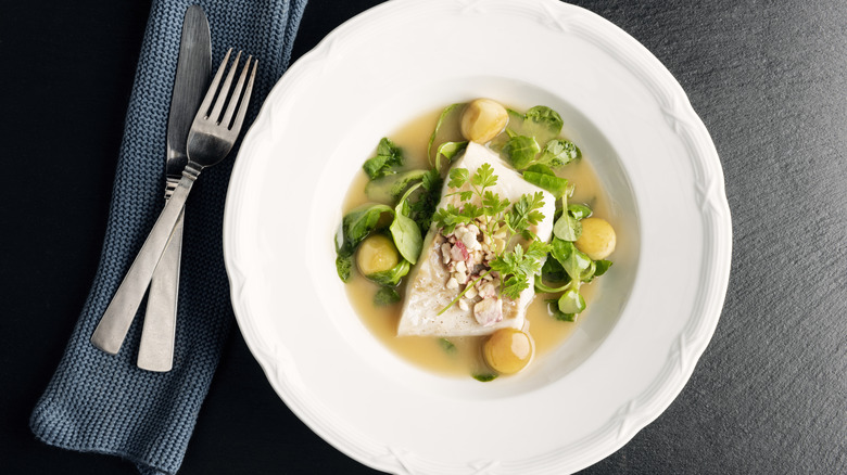 cod dinner on white plate next to utensils