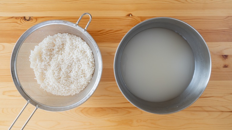 Washed rice next to a bowl of water