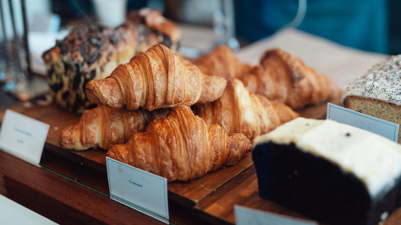 Croissants and cakes are on display in a pastry case