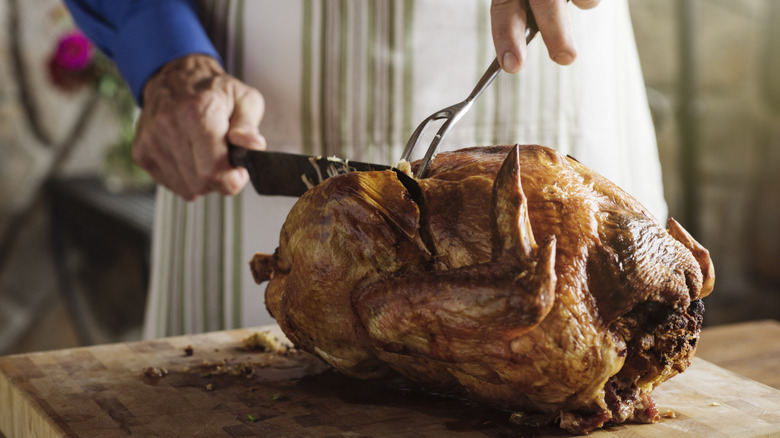 Someone in an apron carves a turkey