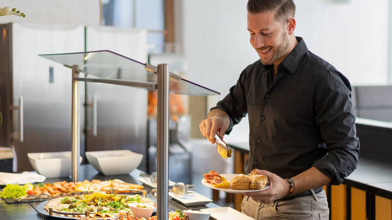 man taking food from buffet