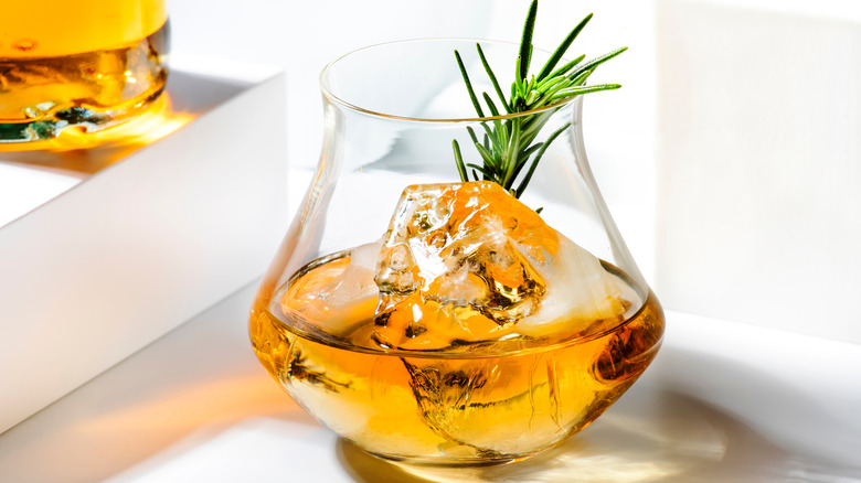 whiskey with single ice shard and rosemary sprig in glass