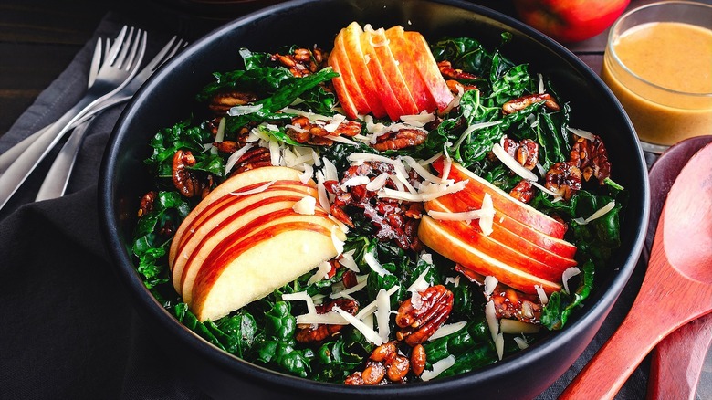 Kale salad with sliced apples, glazed pecans, and shredded cheese