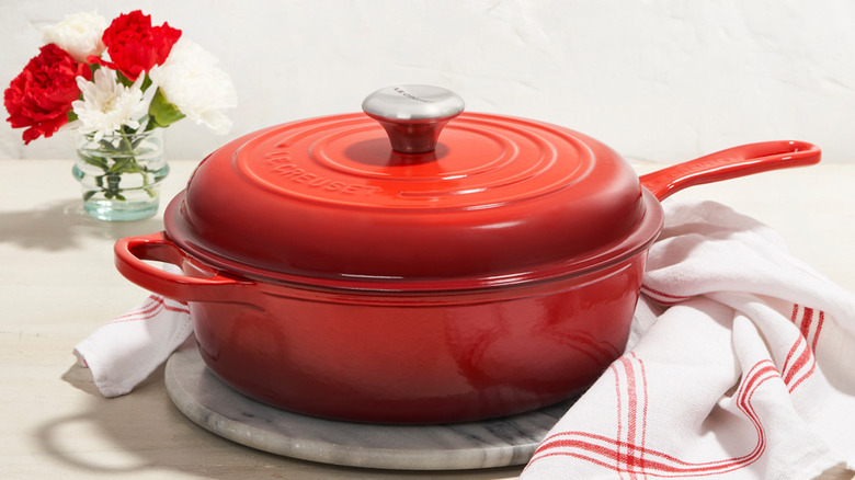Red Le Creuset Dutch oven with flowers in background